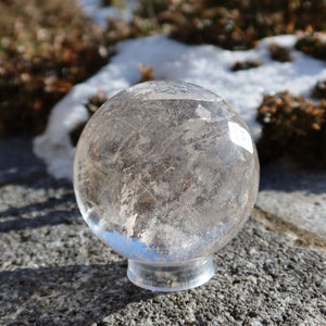 Bergkristall Kugel – Natürliche Kristallkugel 65mm Durchmesser Nr. 35 in natürlichem Licht auf einem Steinuntergrund