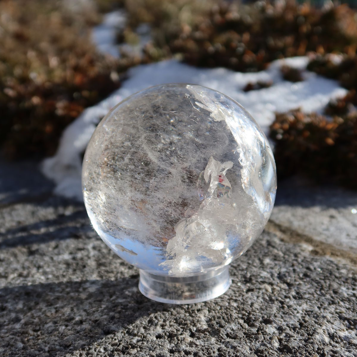 Bergkristall Kugel – Natürliche Kristallkugel 65mm Durchmesser Nr. 36 auf einem felsigen Hintergrund