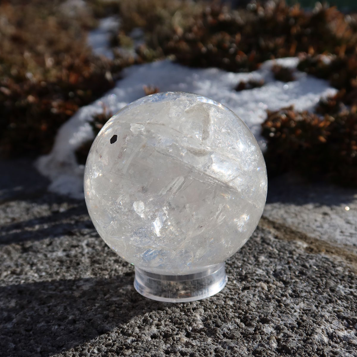 Bergkristall Kugel – Natürliche Kristallkugel 60mm Durchmesser Nr. 39 auf Steinunterlage in der Natur