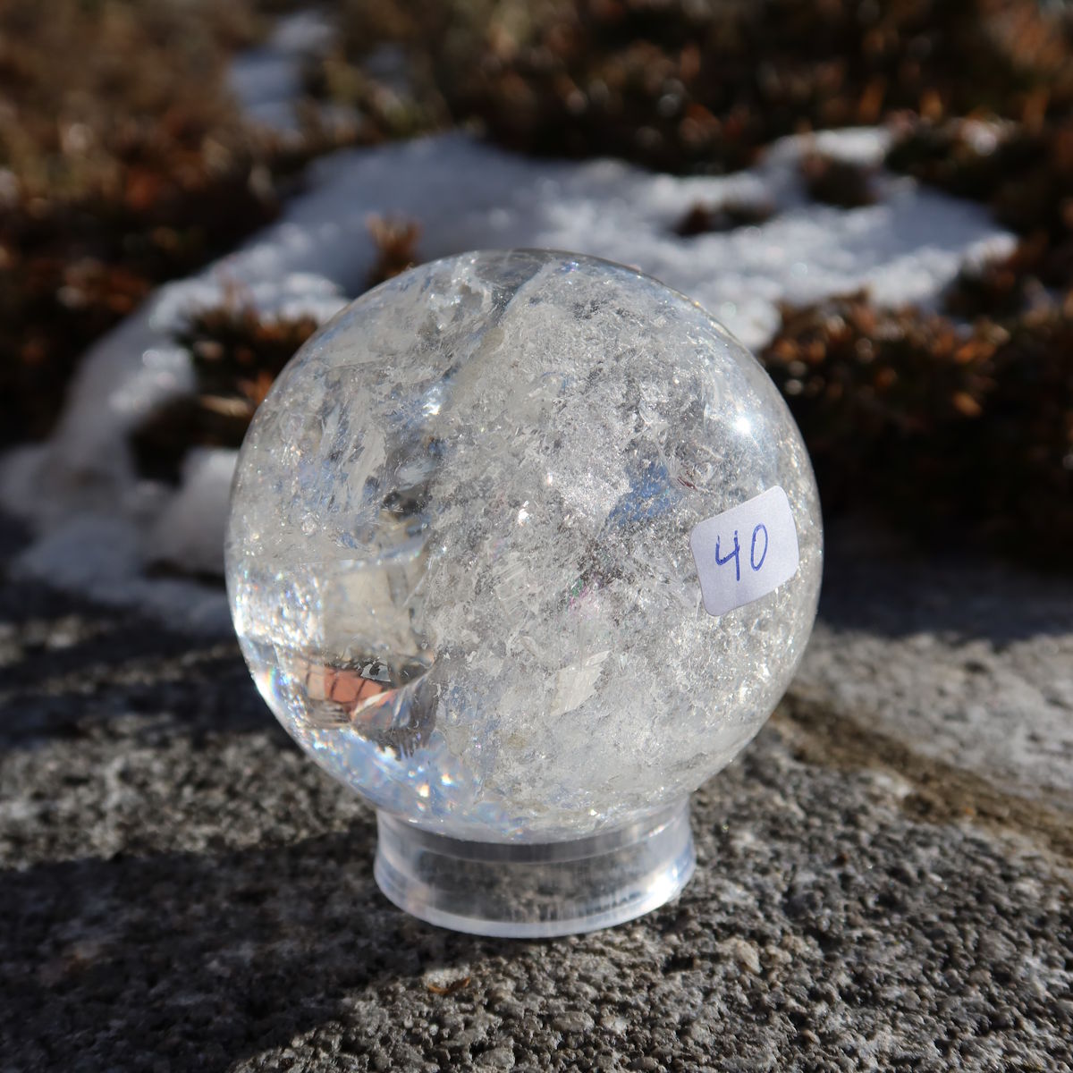 Bergkristall Kugel – Natürliche Kristallkugel 55mm Durchmesser Nr. 40 in der Hand vor einer natürlichen Landschaft