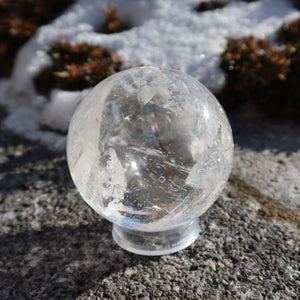 Bergkristall Kugel – Natürliche Kristallkugel 55mm Durchmesser Nr. 40 im Sonnenlicht auf einem Steinuntergrund