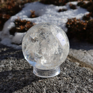 Bergkristall Kugel – Natürliche Kristallkugel 55mm Durchmesser Nr. 44 auf einem Stein im Freien bei Sonnenlicht