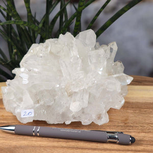Bergkristall Stufe 1A Qualität, 9x15x13 cm - Klarheit und Fokus - UNIKAT Nr. 20, rohe Kristallform auf Holz mit Kugelschreiber zur Größenvergleich