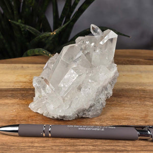 Bergkristall Stufe 1A Qualität, 6x10x7 cm - Klarheit und Fokus - UNIKAT Nr. 30, rohe Kristallstruktur auf Holzoberfläche neben einem Stift