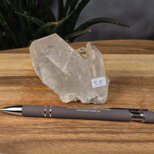 Bergkristall Stufe 1A Qualität, 7x8x5 cm - Klarheit und Fokus - UNIKAT Nr. 35, raw and clear crystal on wooden surface with pen