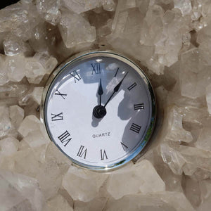Quartz clock embedded in raw Brazilian clear quartz crystal cluster with natural light reflections.