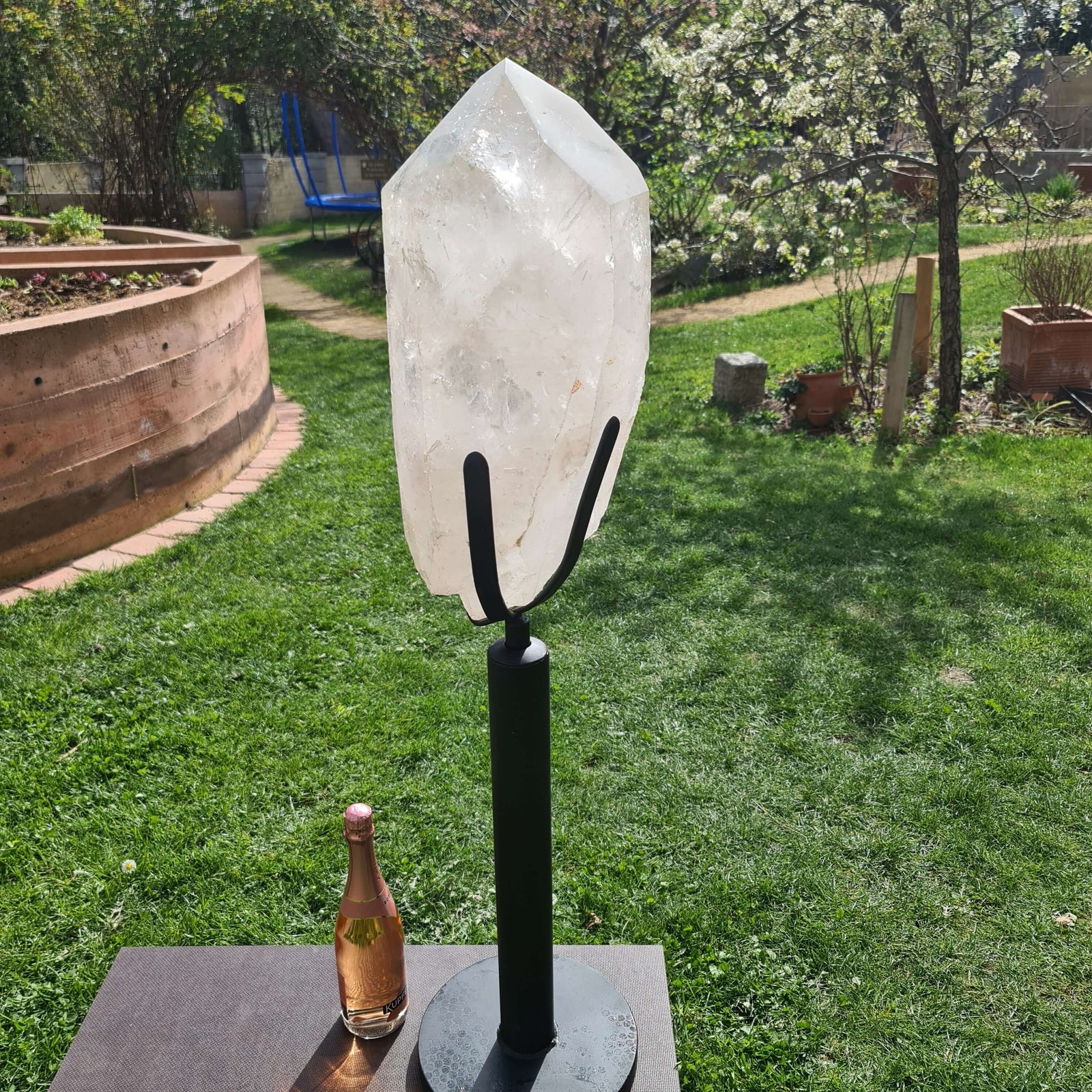Bergkristall XXL Spitze auf Metallständer im Garten, ideal für Meditation und Raumdekoration. Natürlicher Bergkristall XL am Drähständer.