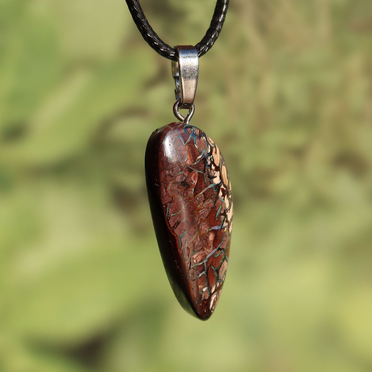 Boulder Opal Anhänger - Positivität und Freude - Nr. 8 mit einzigartigem Muster und Silberöse auf grünem Hintergrund