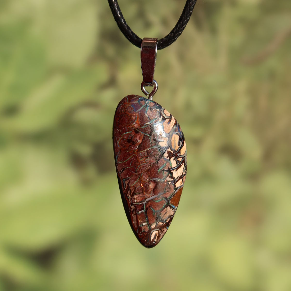 Boulder Opal Anhänger - Positivität und Freude - Nr. 8 mit einzigartigem Muster und Silberöse auf grünem Hintergrund