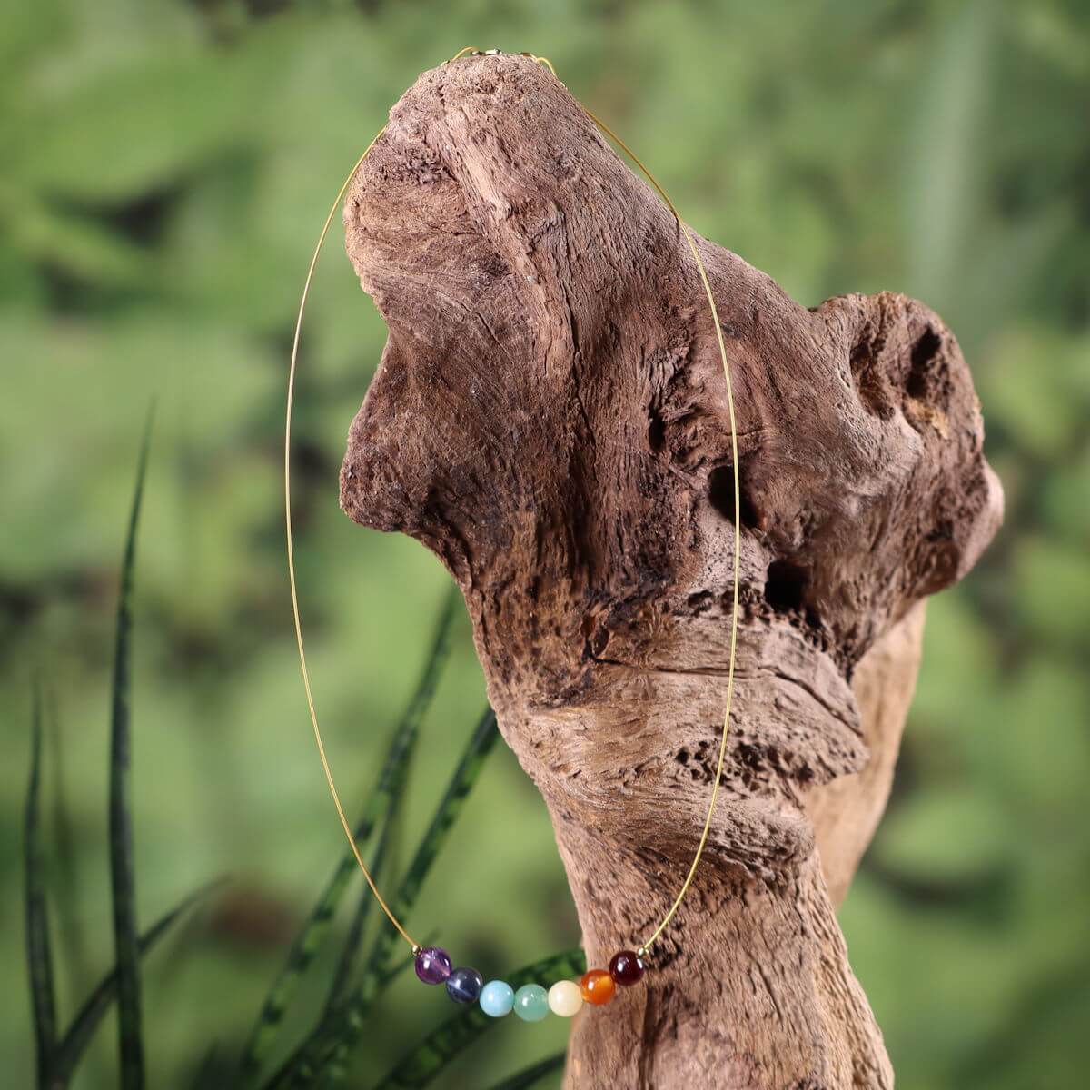 Chakra Edelsteinkette 40cm mit sieben farbigen Steinen für Balance und Ausgeglichenheit, elegant präsentiert auf Holz.
