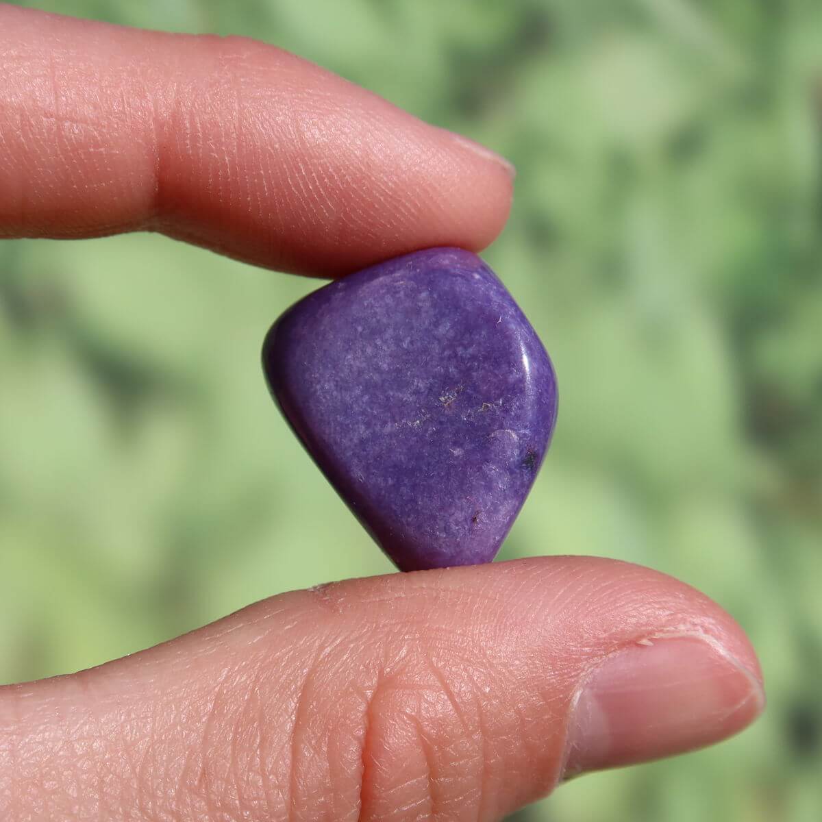 Hand holding a deep violet 20mm Charoit stone, showcasing its unique patterns, available for online purchase in Graz and Wiener Neustadt.