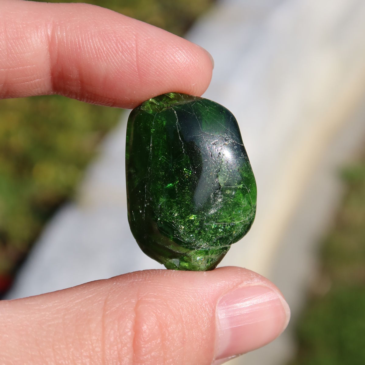 Natürlicher Chromdiopsid Handschmeichler 38mm - Kreativität und Leichtigkeit - UNIKAT Nr. 15 in der Hand gehalten, tiefgrünes Schimmern.