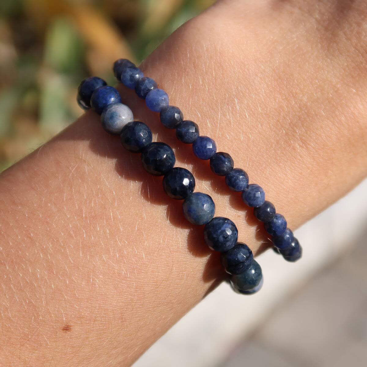 Faceted Dumortierite gemstone bracelet in blue tones on wrist, 4-6-8mm beads, promotes calm and clarity, suitable for stress relief.