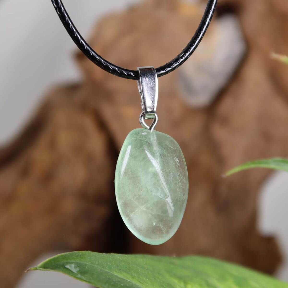 Grüner Fluorit Anhänger an schwarzer Kette mit Silberöse, einzigartiges Unikat Nr. 5, Darstellung vor naturbelassenem Hintergrund