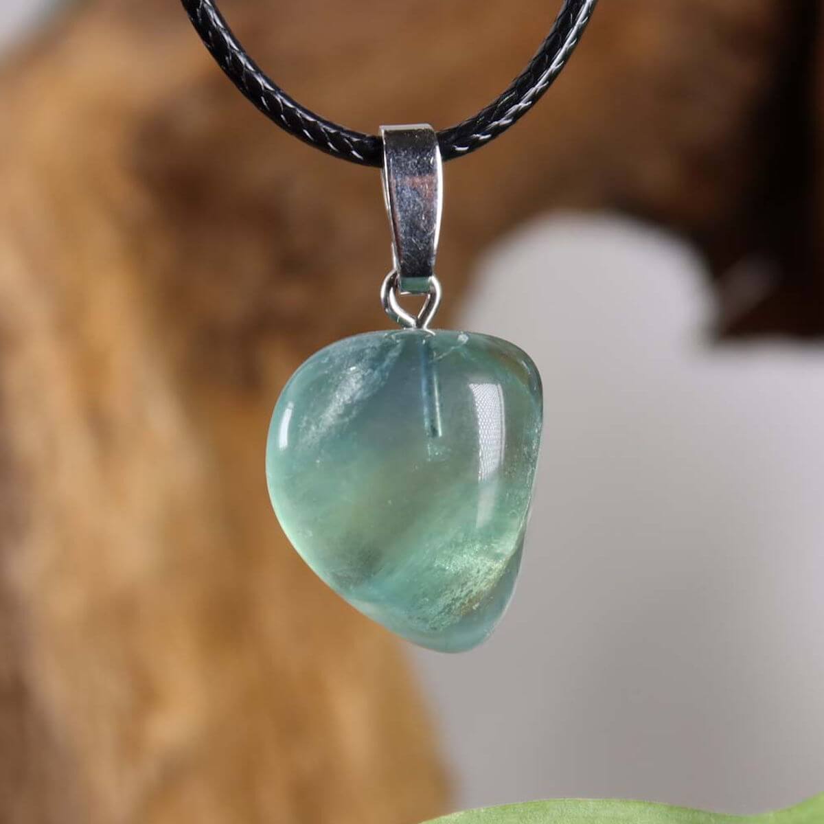 Unique fluorite pendant with silver rhodium-plated loop, showcasing gradient green and violet hues, on black cord.