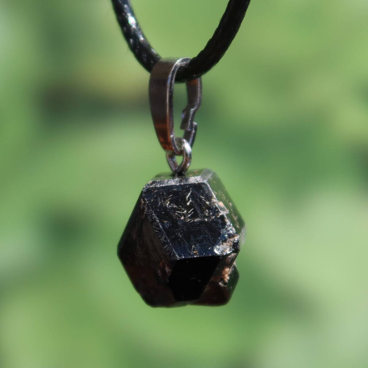 Natürlicher Granat Melanit Anhänger - Standfestigkeit und Stabilität - UNIKAT Nr. 2, eleganter schwarzer Edelstein auf grünem Hintergrund