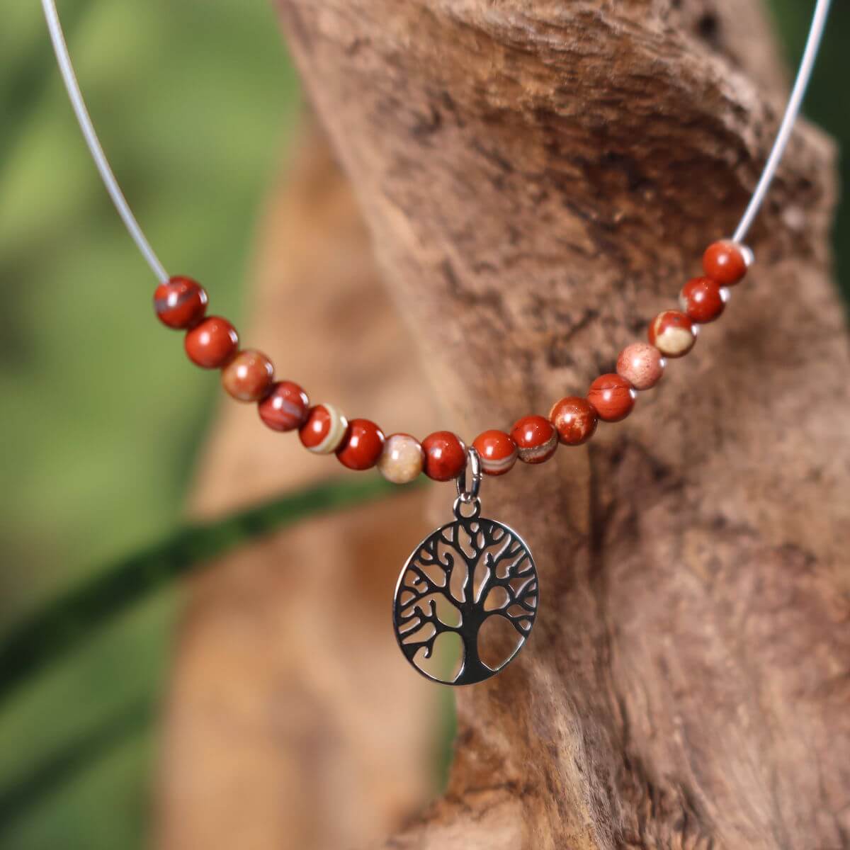 Red Jasper necklace with Tree of Life pendant on driftwood, symbolizing grounding and strength, perfect for elegant daily wear.