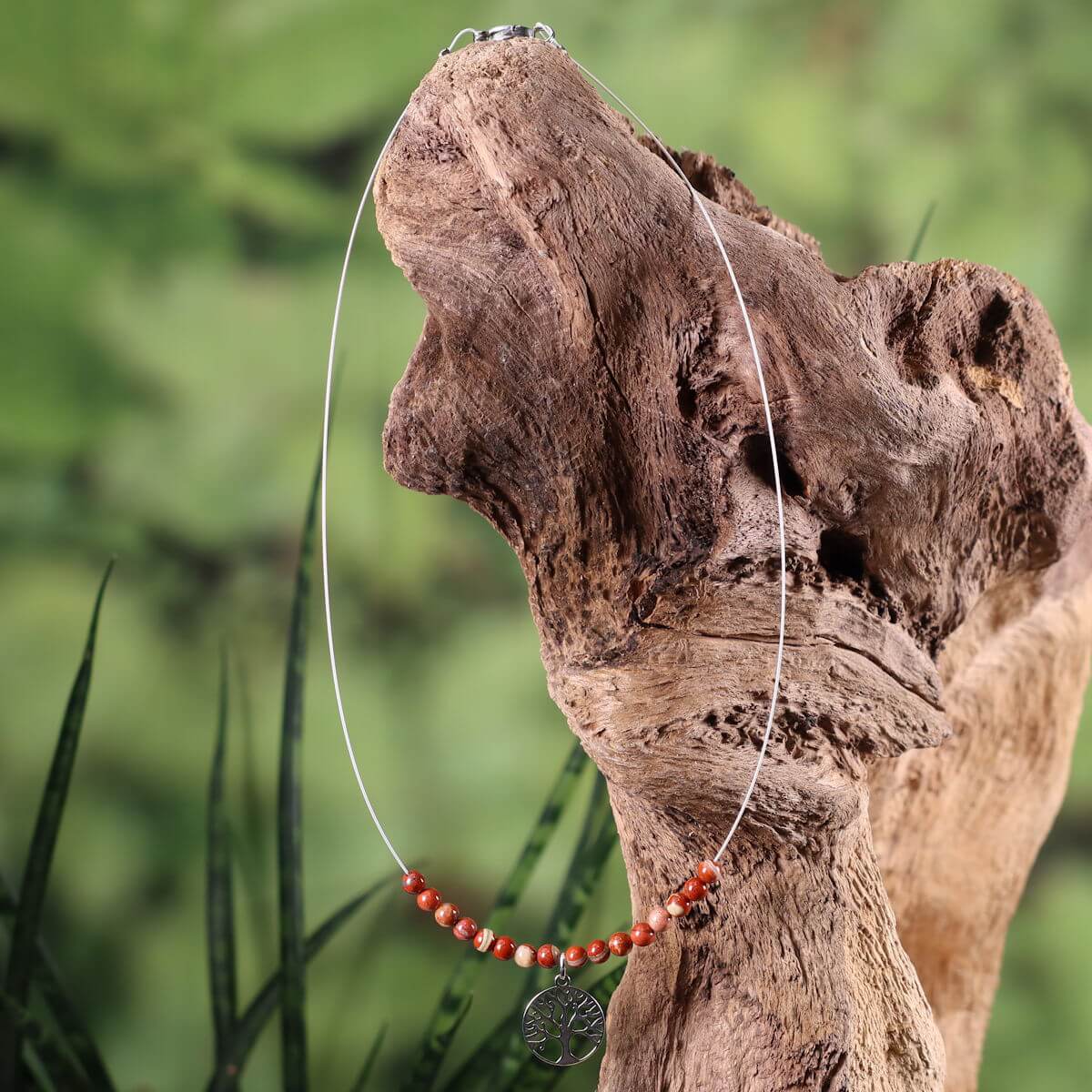Red Jasper necklace with Tree of Life pendant on driftwood, symbolizing grounding and strength, perfect for elegant daily wear.