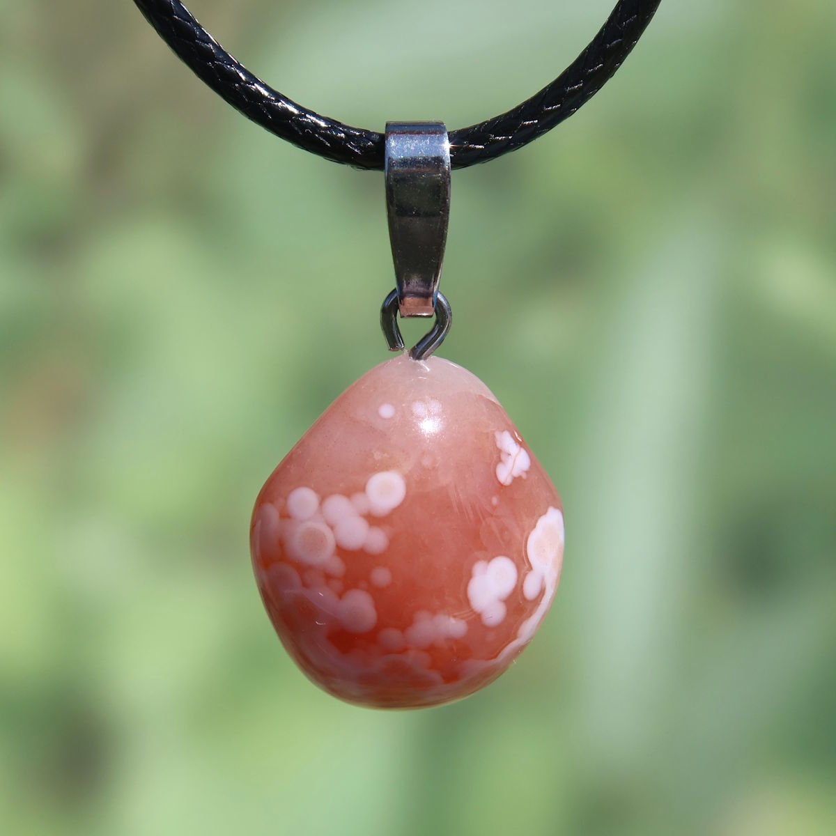 Natürlicher Karneol Anhänger in 20mm, lebendig orange-rot, mit einzigartigen Maserungen auf schwarzem Band. Fördert Lebensfreude & Energie.