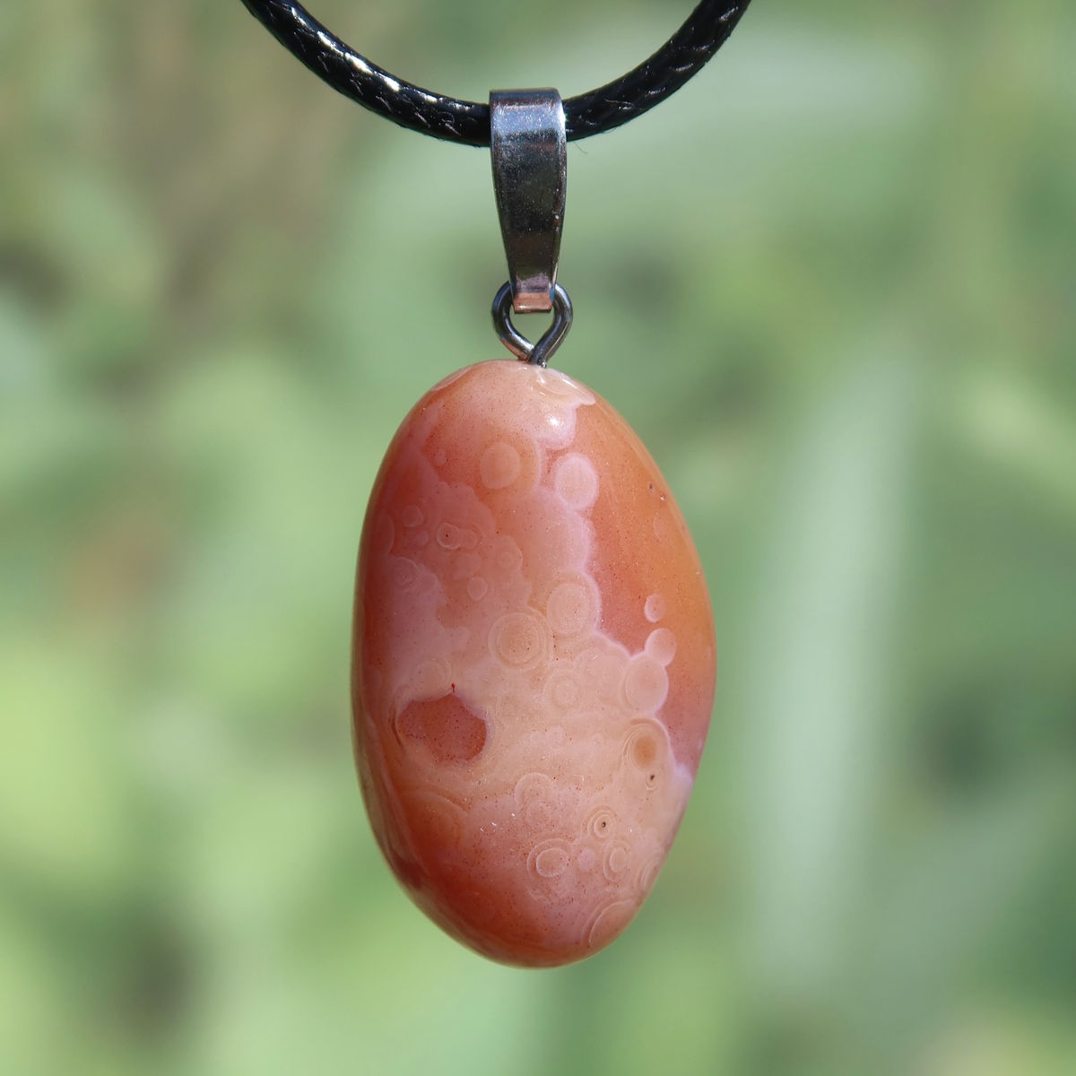 Karneol Anhänger 30mm in lebendigem Orange-Rot, einzigartig mit natürlichen Maserungen, auf einer schwarzen Kordel präsentiert.