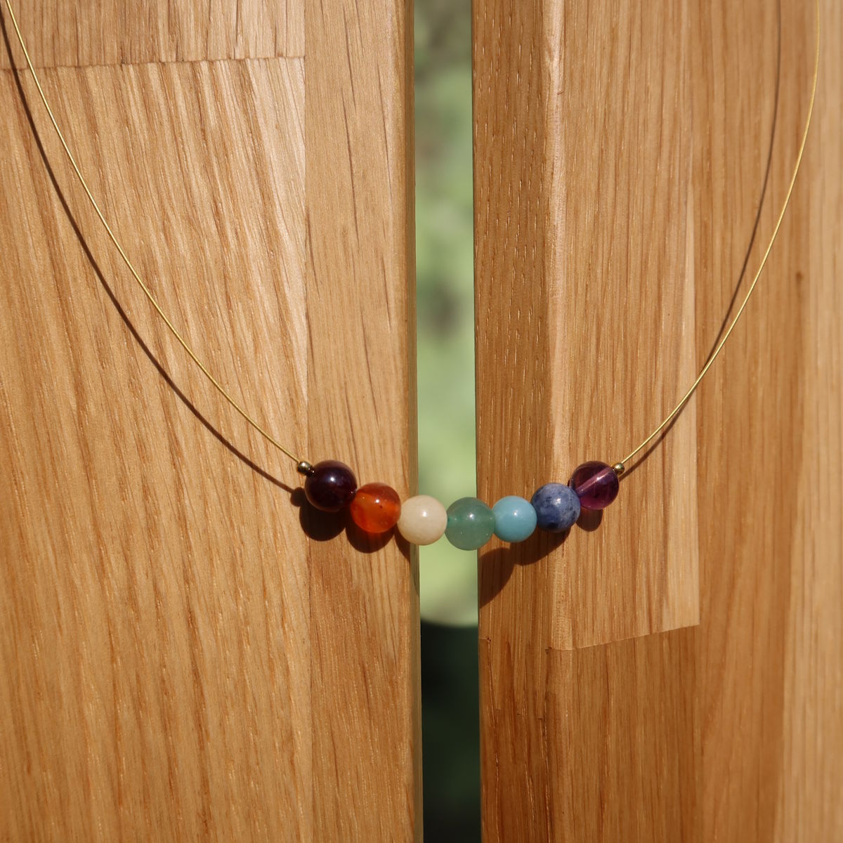 Chakra Edelsteinkette 40cm aus sieben Chakren Edelsteinen auf einem Holzständer, ideal für Balance und Ausgeglichenheit.