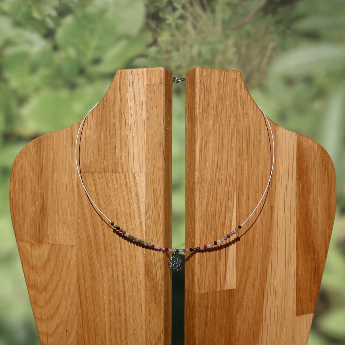 Turmalin bunt Edelsteinkette mit Blume des Lebens in 40cm Länge, für Harmonie und Balance, auf einer Holz-Auslage präsentiert.