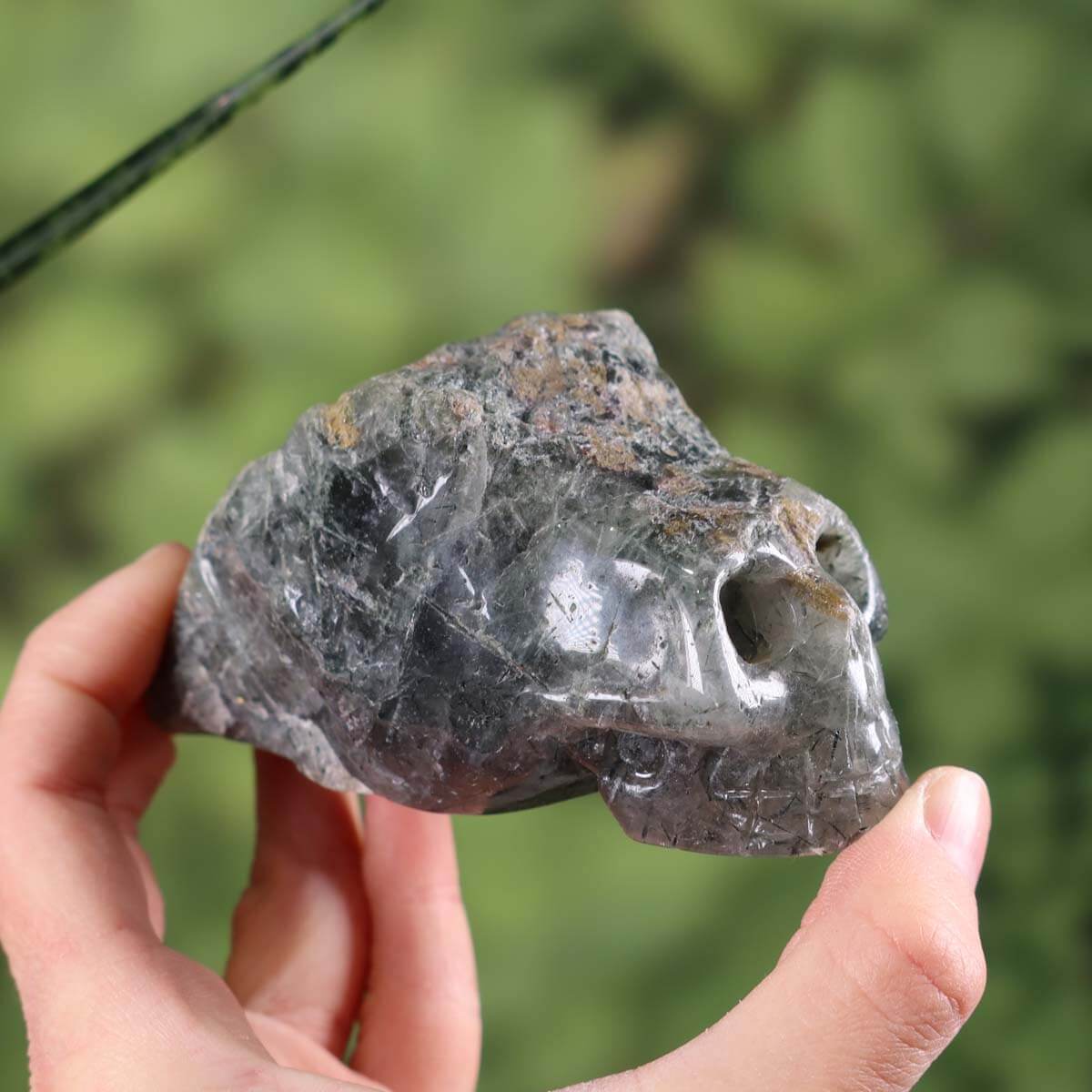 Handcrafted Actinolite Quartz Crystal Skull in Unique Shape, 9x5 cm, Collector's Item, held in hand against a green background.