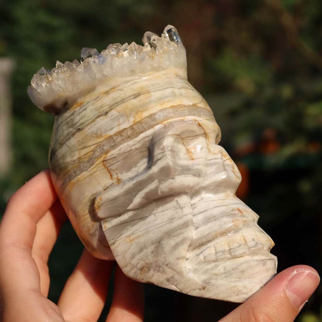 Hand holding handcrafted crystal skull made from unique gemstone, perfect for collectors. Kristallschädel online kaufen.