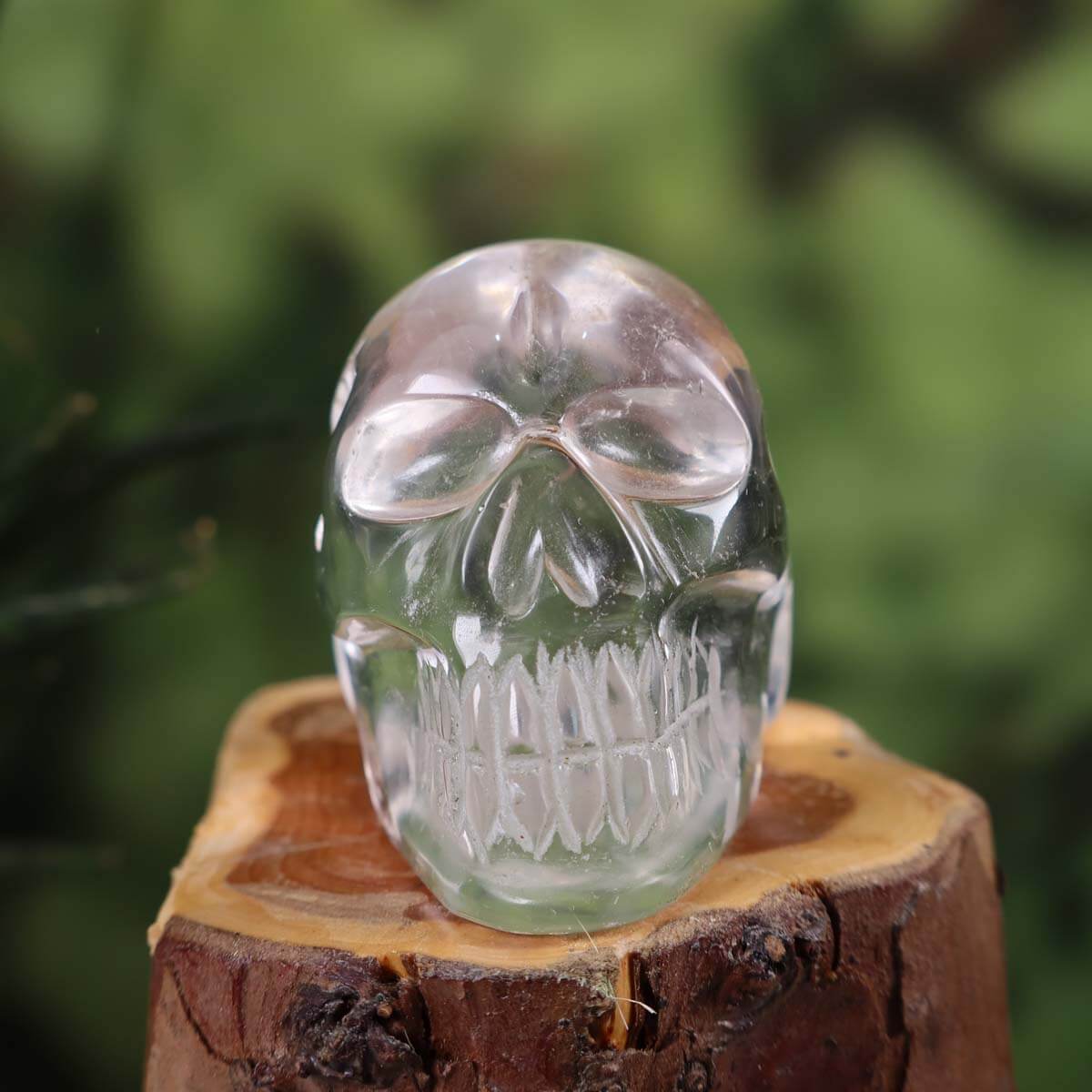 Handcrafted crystal skull made from clear quartz with unique design, displayed on a wooden base.