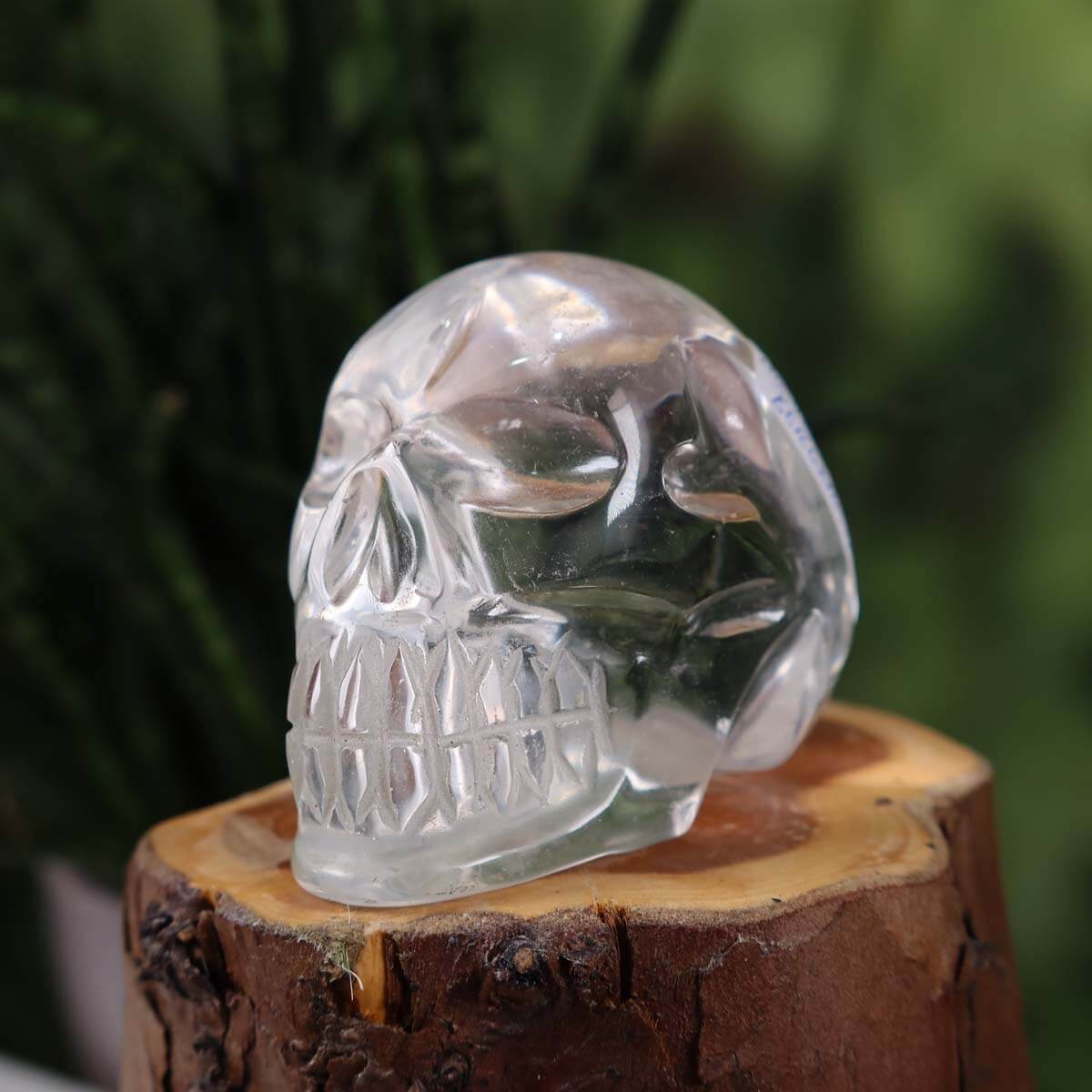 Handcrafted crystal skull made from clear quartz with unique design, displayed on a wooden base.