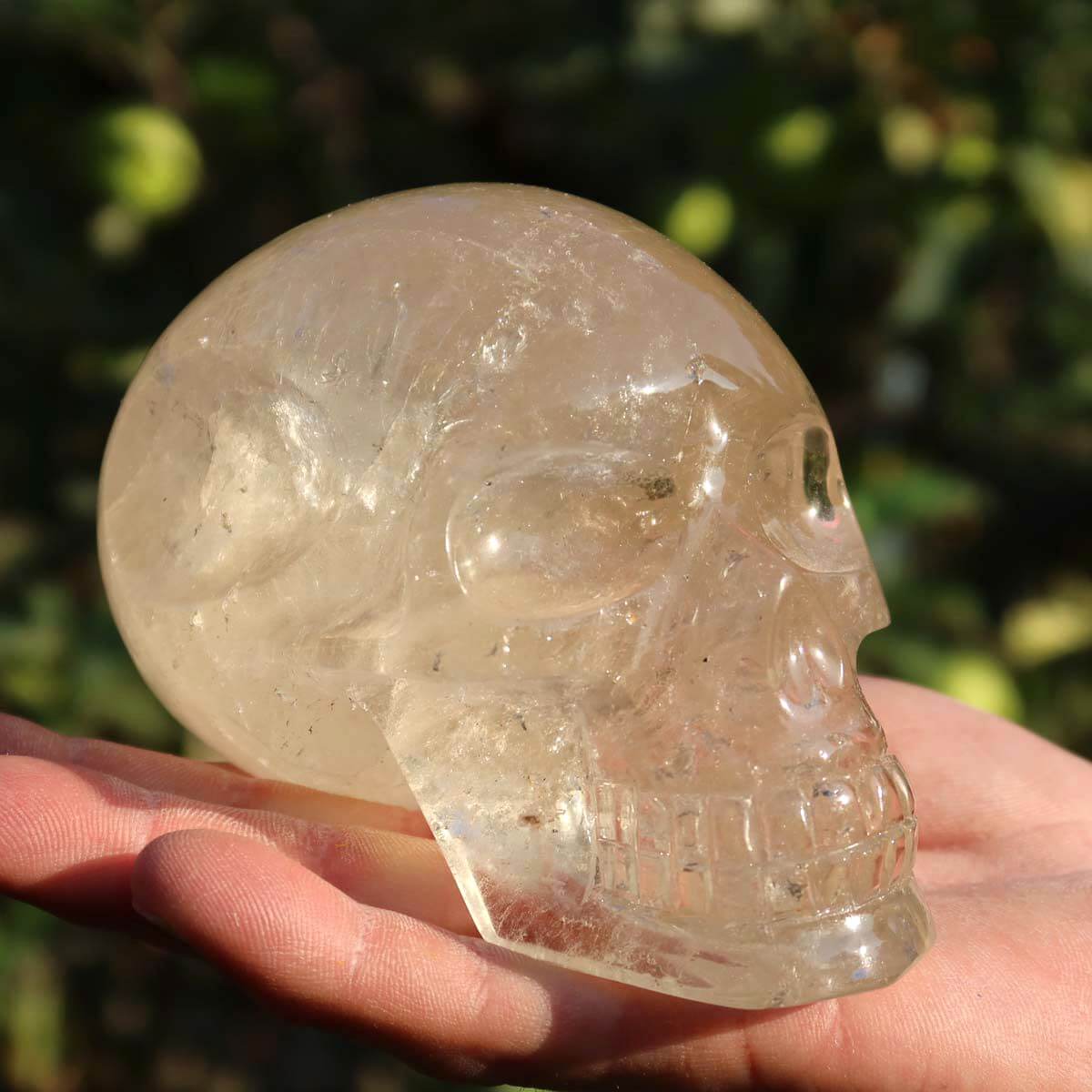 Hand holding handcrafted Citrine crystal skull, unique gemstone carving for collectors, available at Steinwelten.