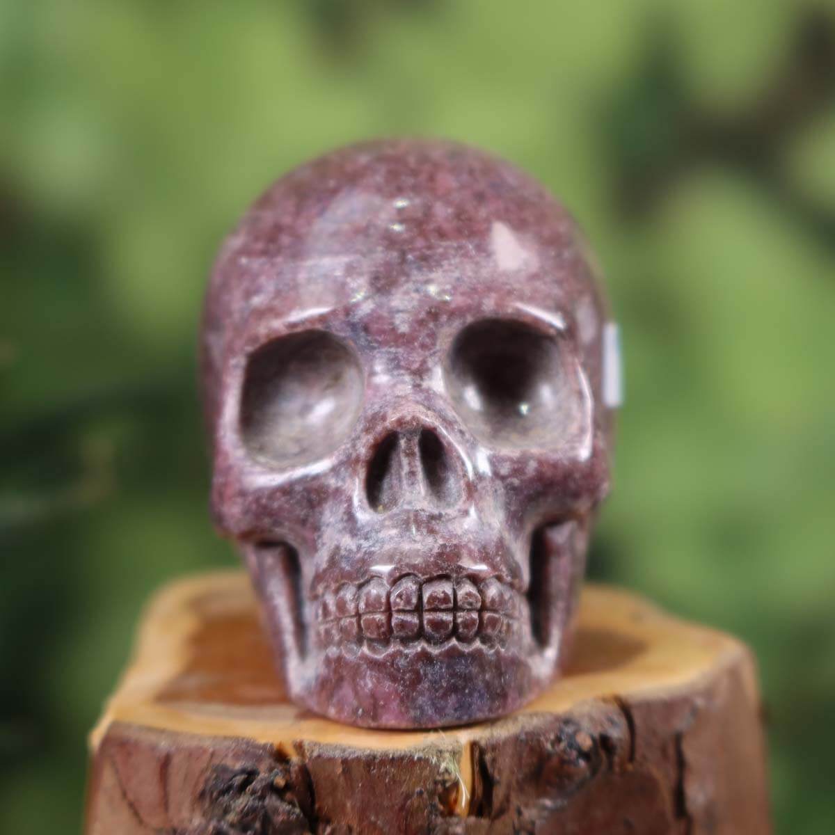 Handcrafted natural stone crystal skull, unique amethyst carving, approximately 7x6 cm, displayed on wooden base.