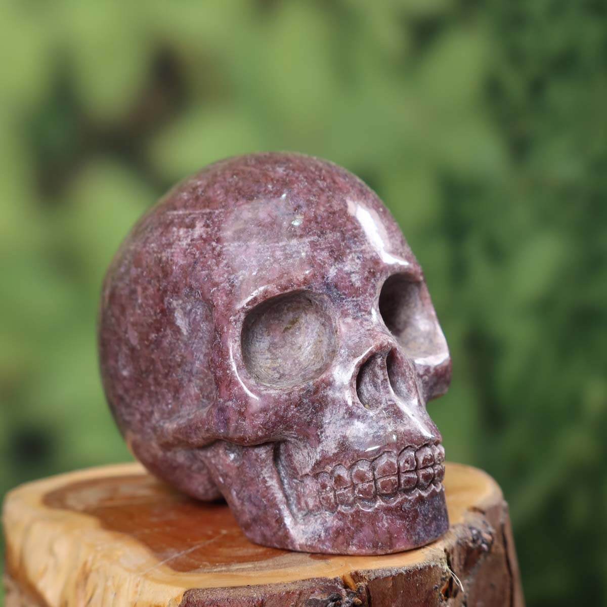 Handcrafted natural stone crystal skull, unique amethyst carving, approximately 7x6 cm, displayed on wooden base.