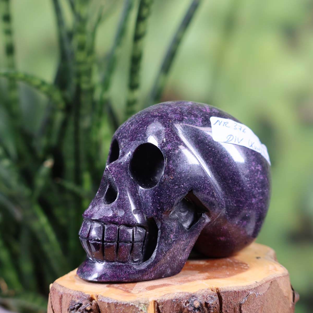 Handcrafted natural stone crystal skull, unique 7x6 cm design, purple gemstone sculpture on wooden surface.