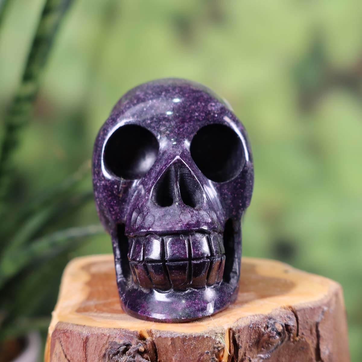 Handcrafted natural stone crystal skull, unique 7x6 cm design, purple gemstone sculpture on wooden surface.