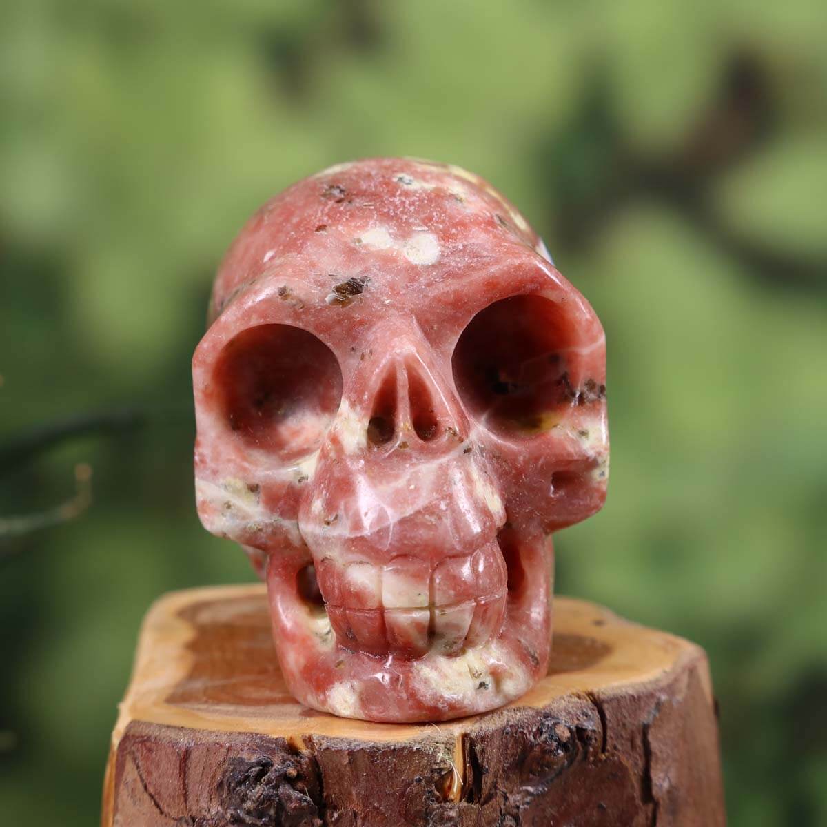 Handcrafted crystal skull made from natural stone with unique patterns, collector's item, 7x6 cm, held in hand.