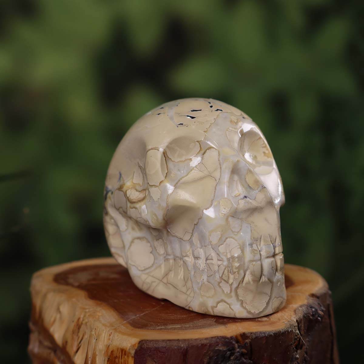 Handcrafted natural stone crystal skull, 7x5 cm, unique design with intricate detailing, displayed on wooden base.