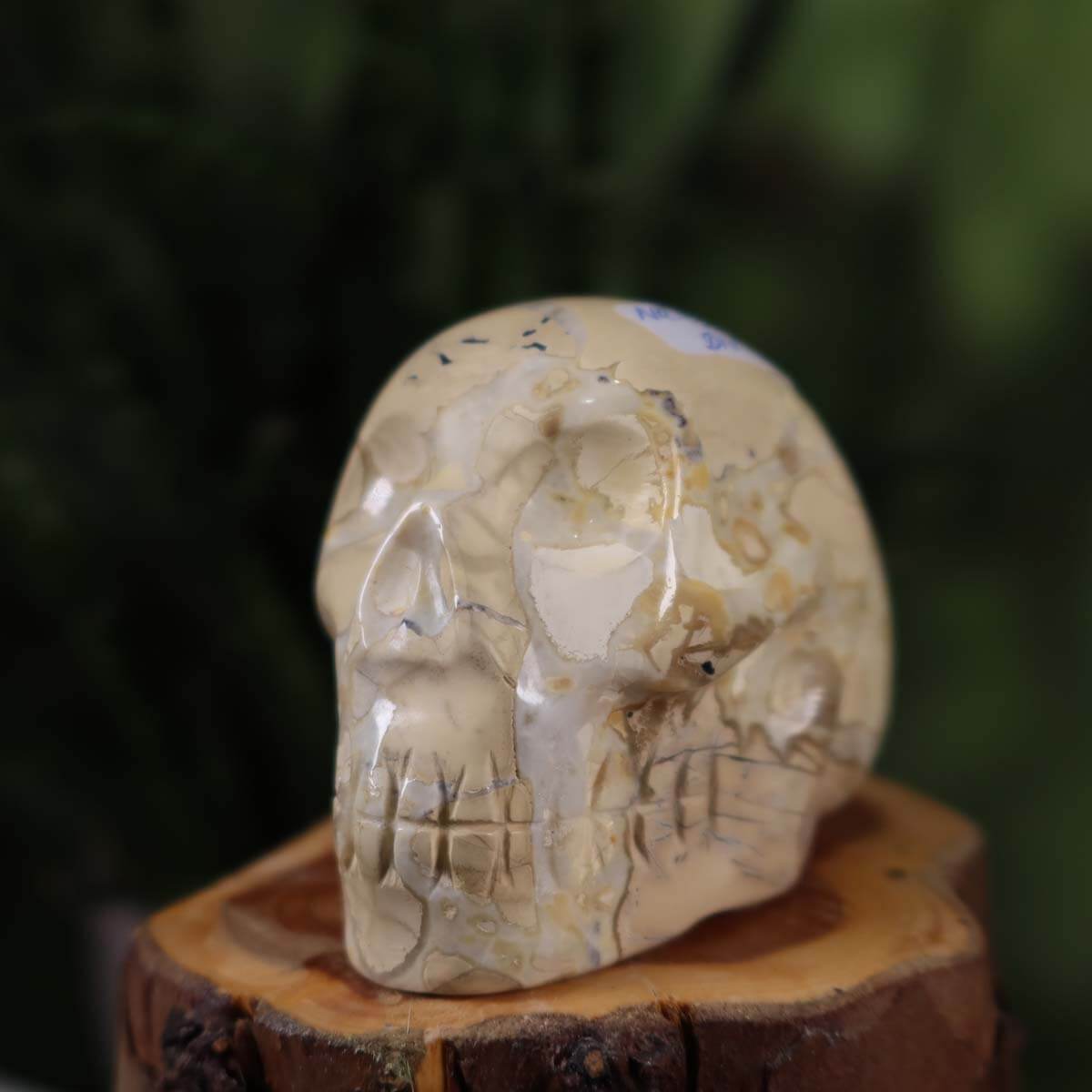 Handcrafted natural stone crystal skull, 7x5 cm, unique design with intricate detailing, displayed on wooden base.
