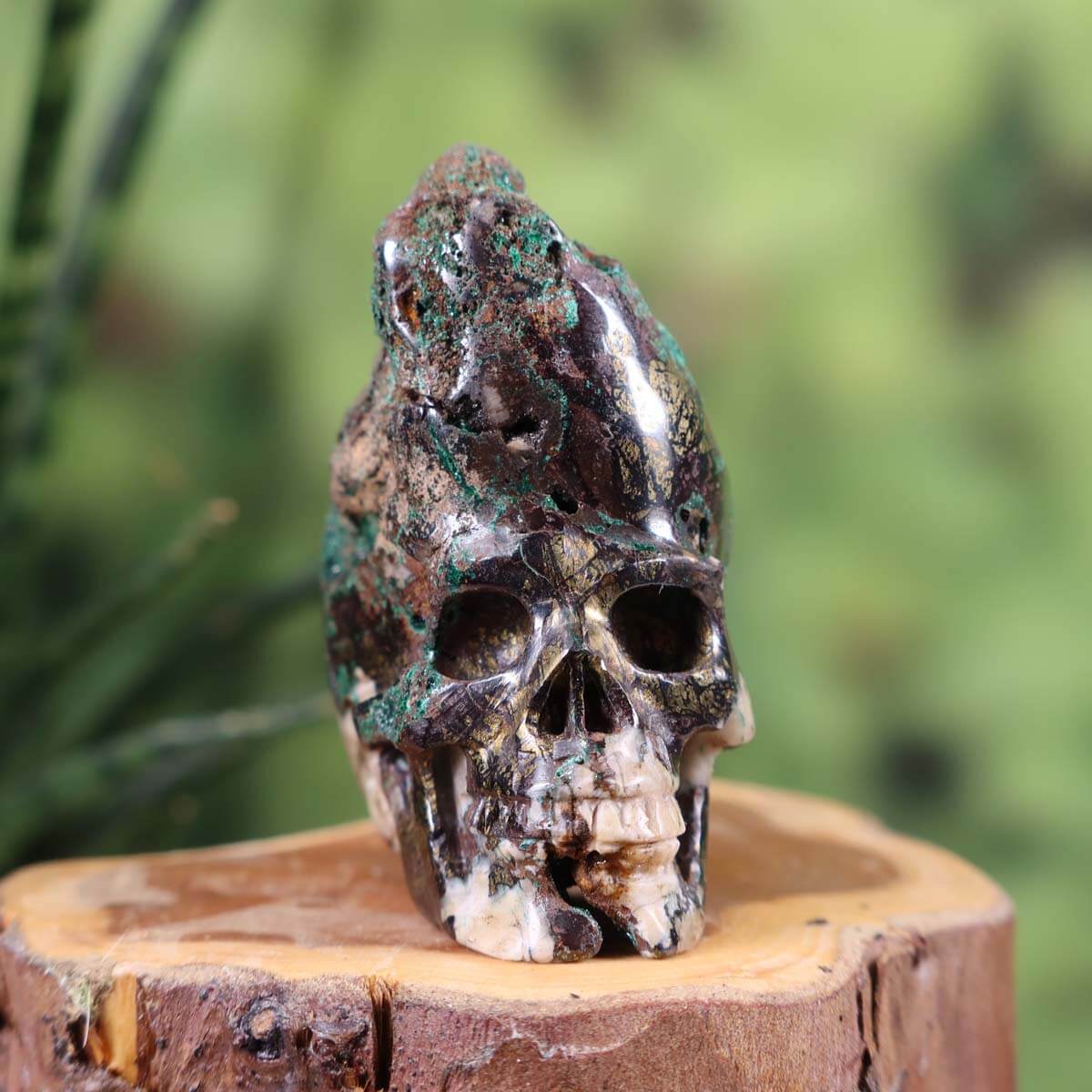 Handcrafted Garnet Uvarovite Crystal Skull on wooden stump, showcasing unique shape and craftsmanship, collectible size 5x6 cm.