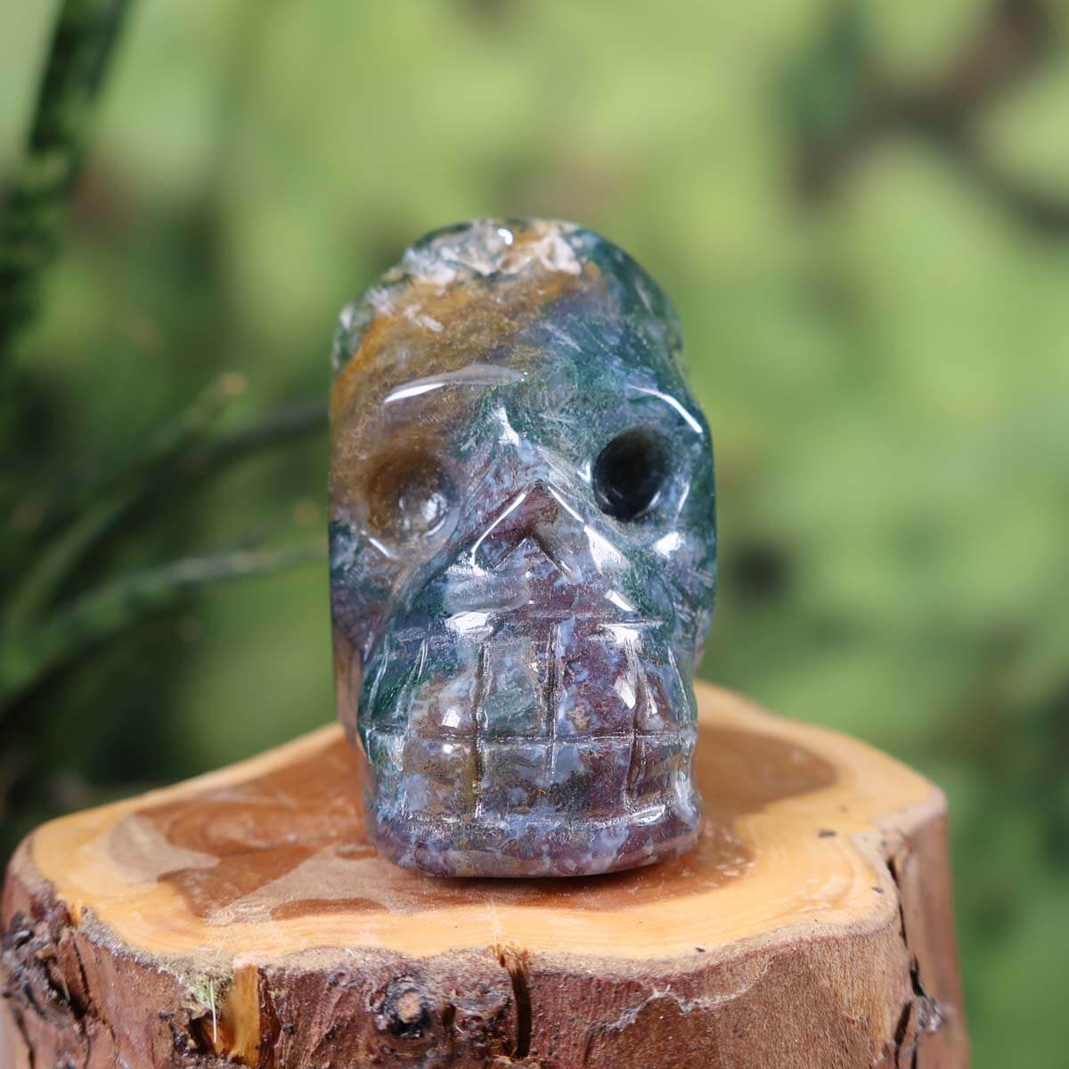 Handcrafted moss agate crystal skull collectible on wooden base