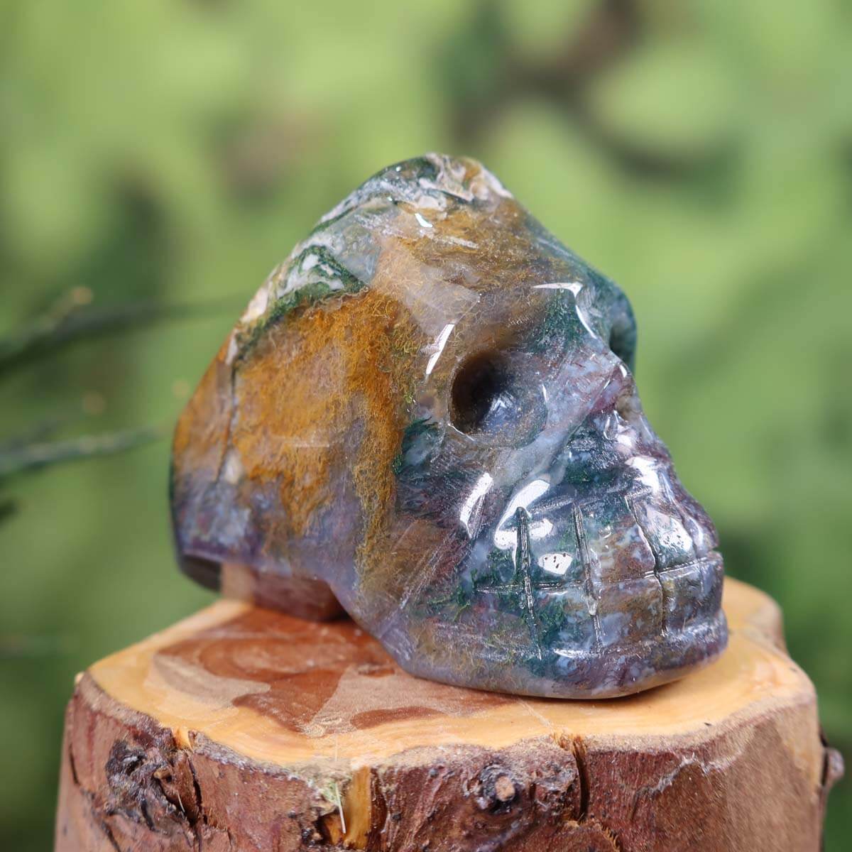 Handcrafted moss agate crystal skull collectible on wooden base