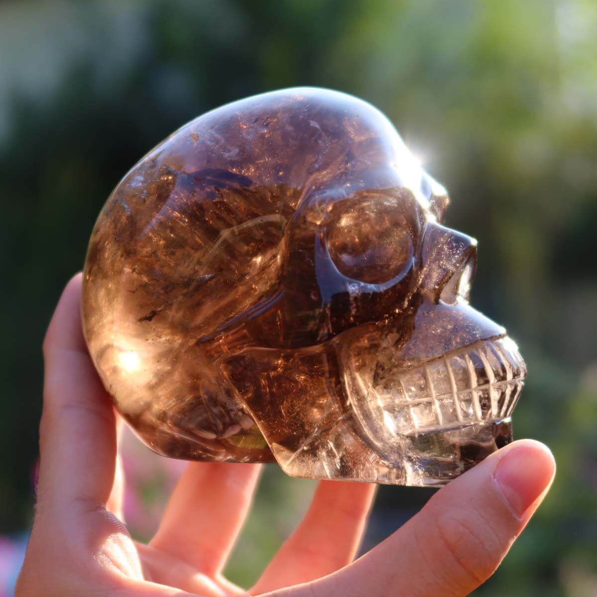 Handcrafted smoke quartz crystal skull, 10x8 cm, unique gemstone art piece reflecting light. Approx. 0.7 kg. Totenkopf Steinwelten.