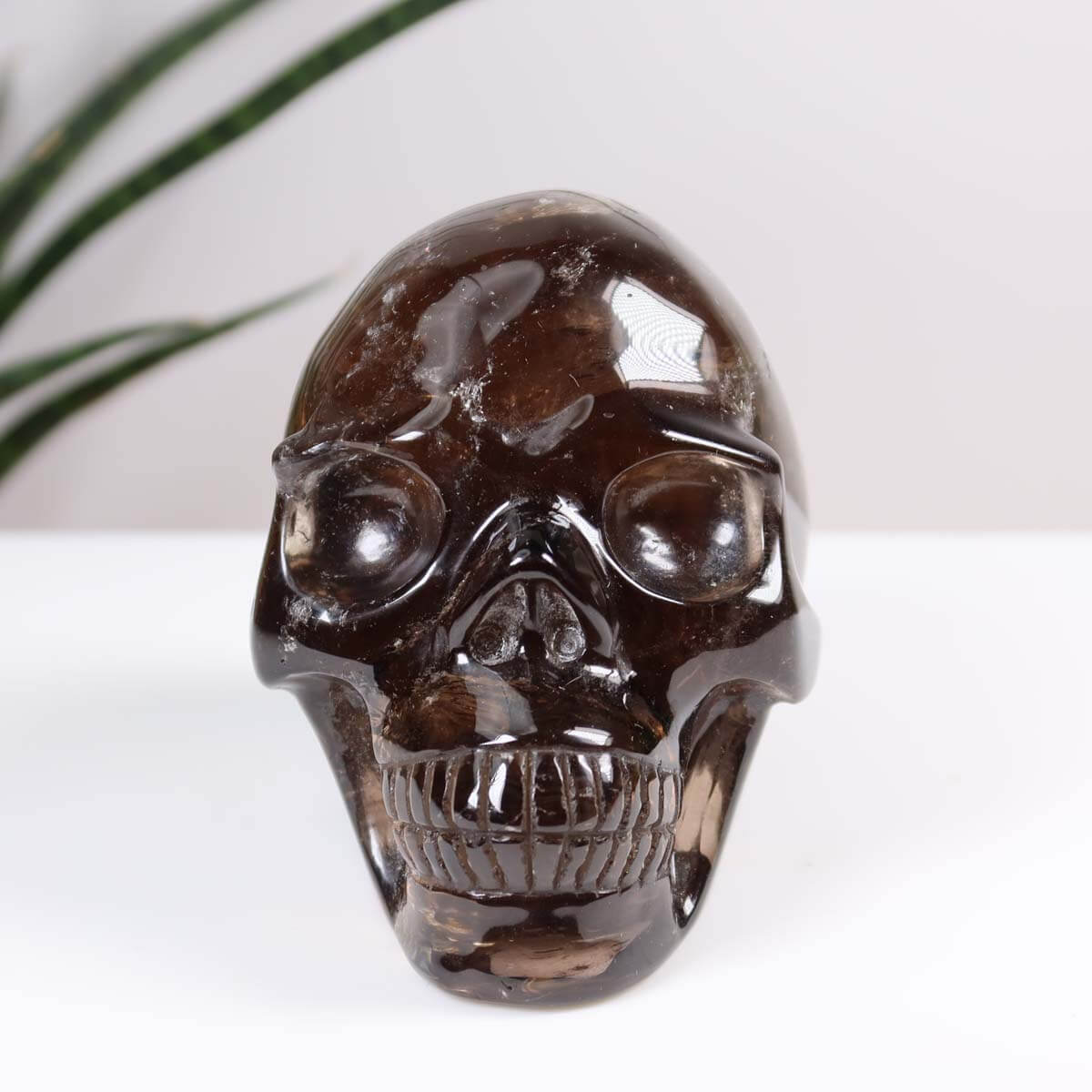 Handcrafted smoke quartz crystal skull, 10x8 cm, unique gemstone art piece reflecting light. Approx. 0.7 kg. Totenkopf Steinwelten.