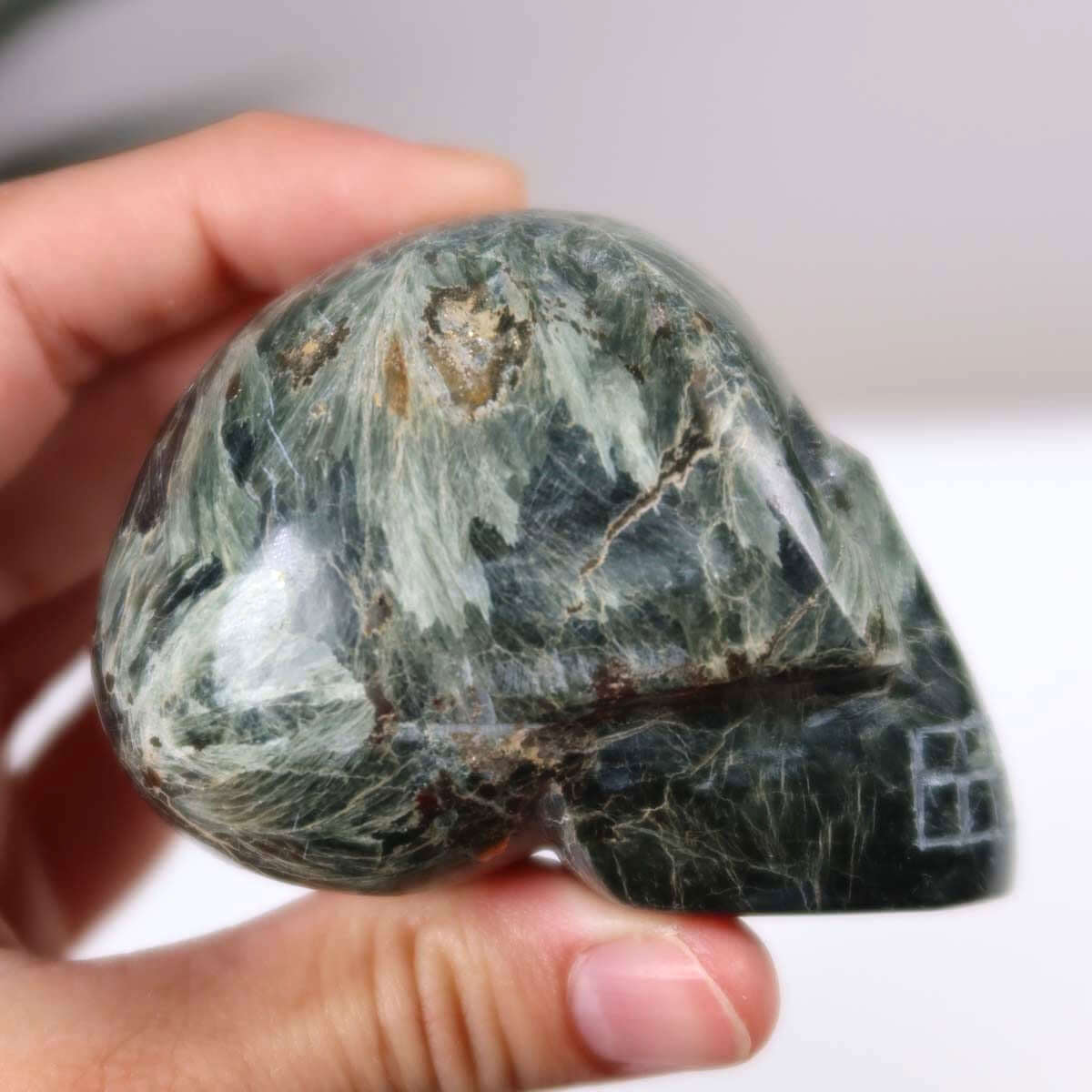 Handcrafted Seraphinite Klinochlor crystal skull, unique collectible gemstone sculpture.