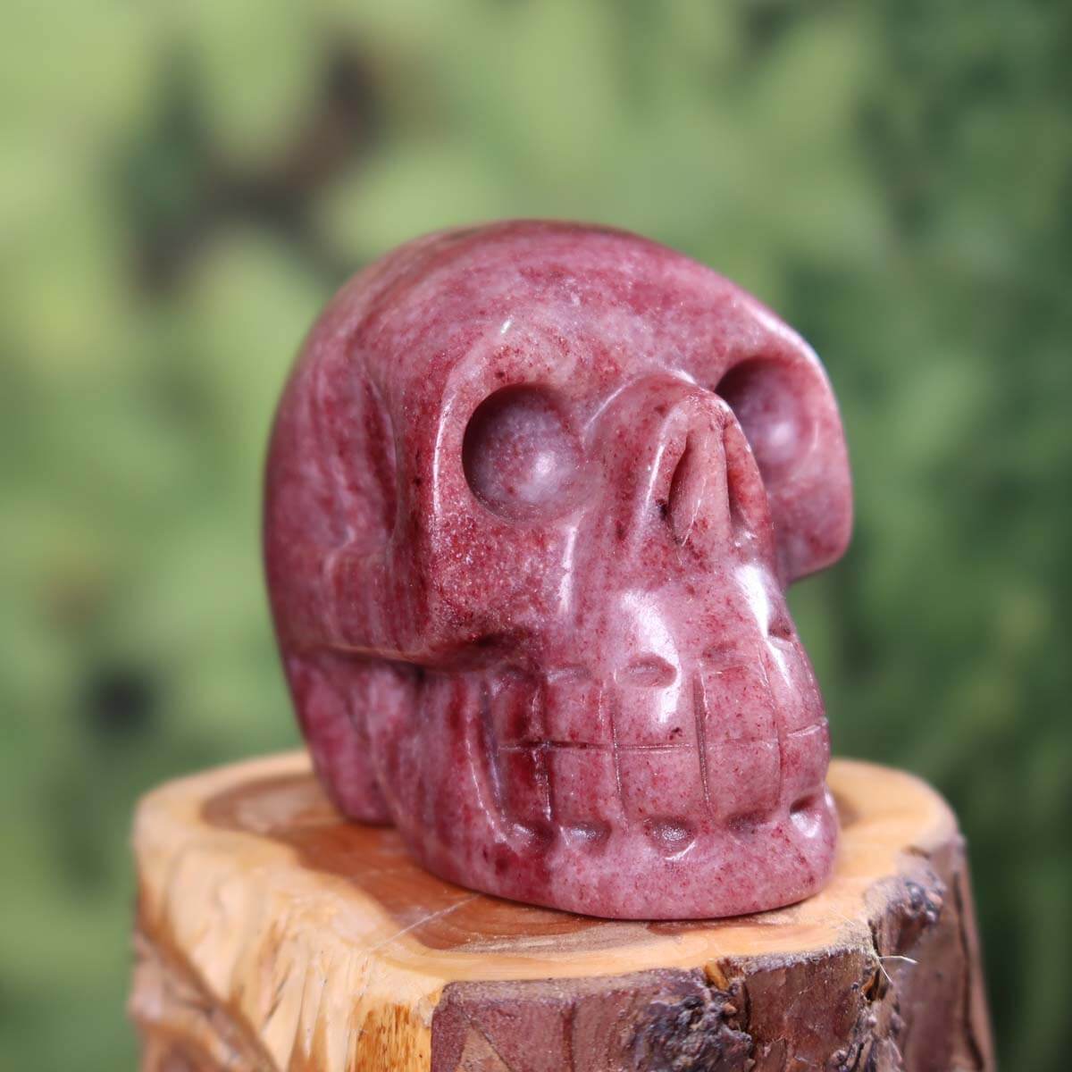 Handcrafted Thulit crystal skull, unique collector's item, displayed on wood, 7x6 cm, featuring exceptional craftsmanship.
