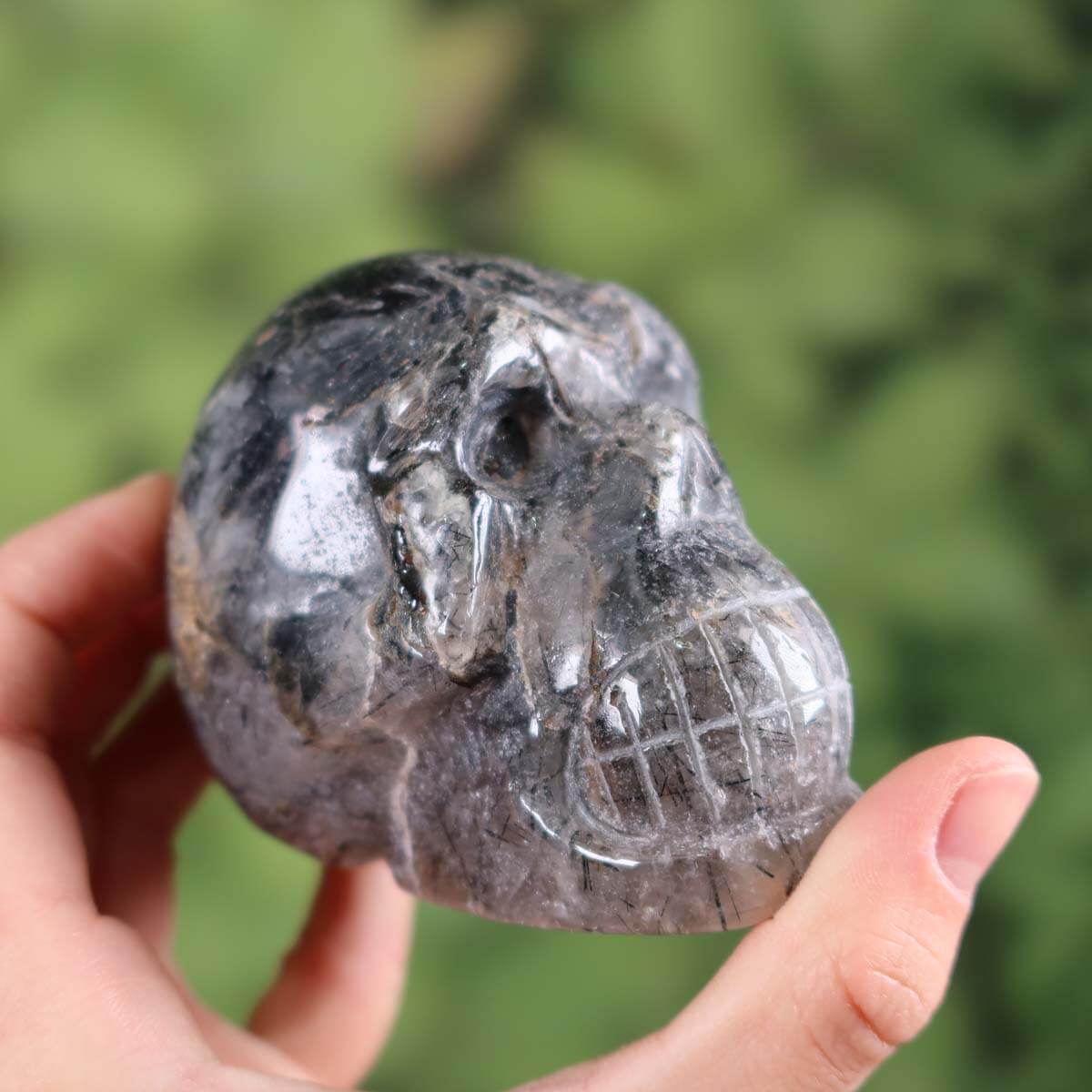 Handcrafted tourmaline quartz crystal skull, unique design, 7x6 cm, collector's item on wooden stand.