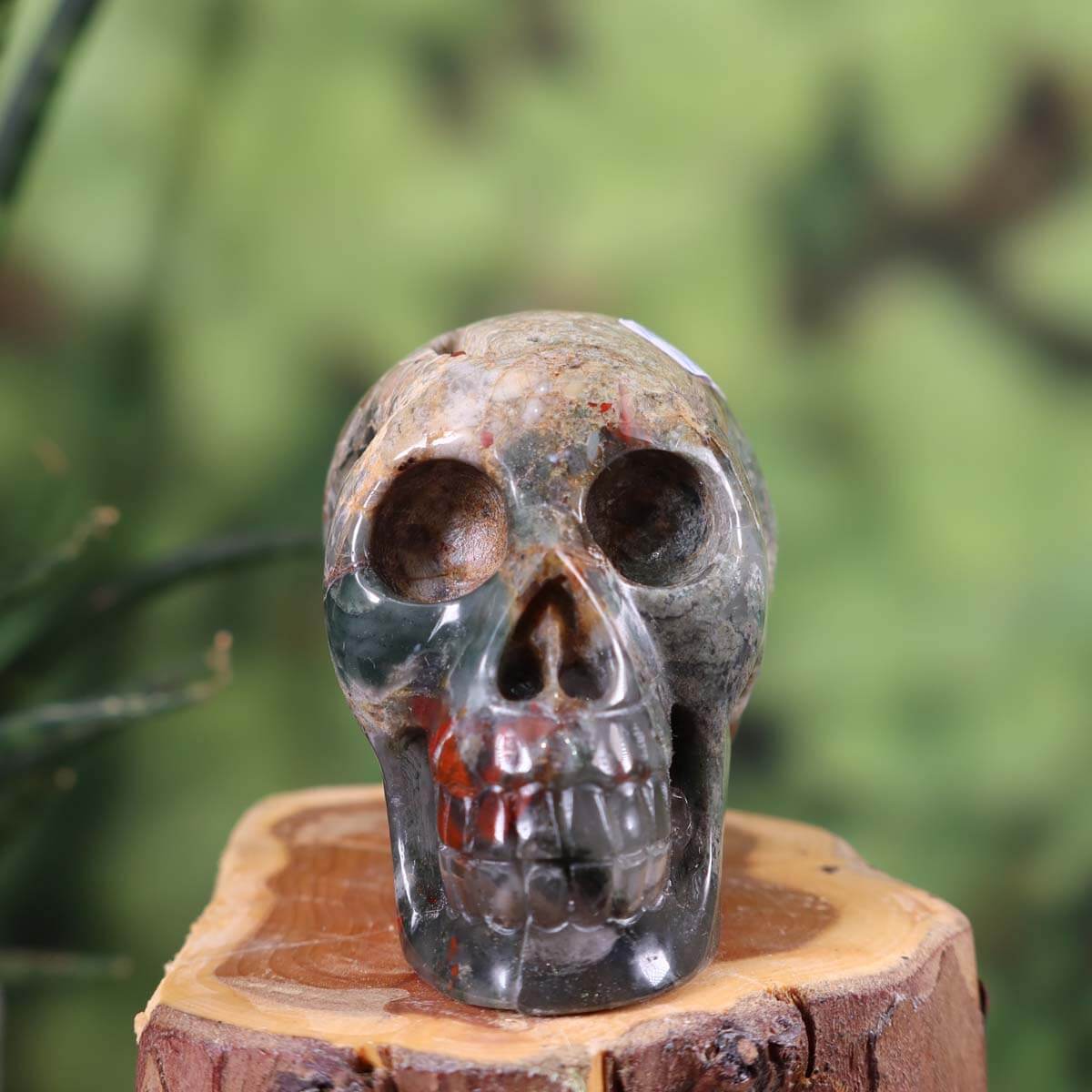 Handcrafted volcanic jasper crystal skull sculpture, unique collector's item with intricate details, set on a wooden base.