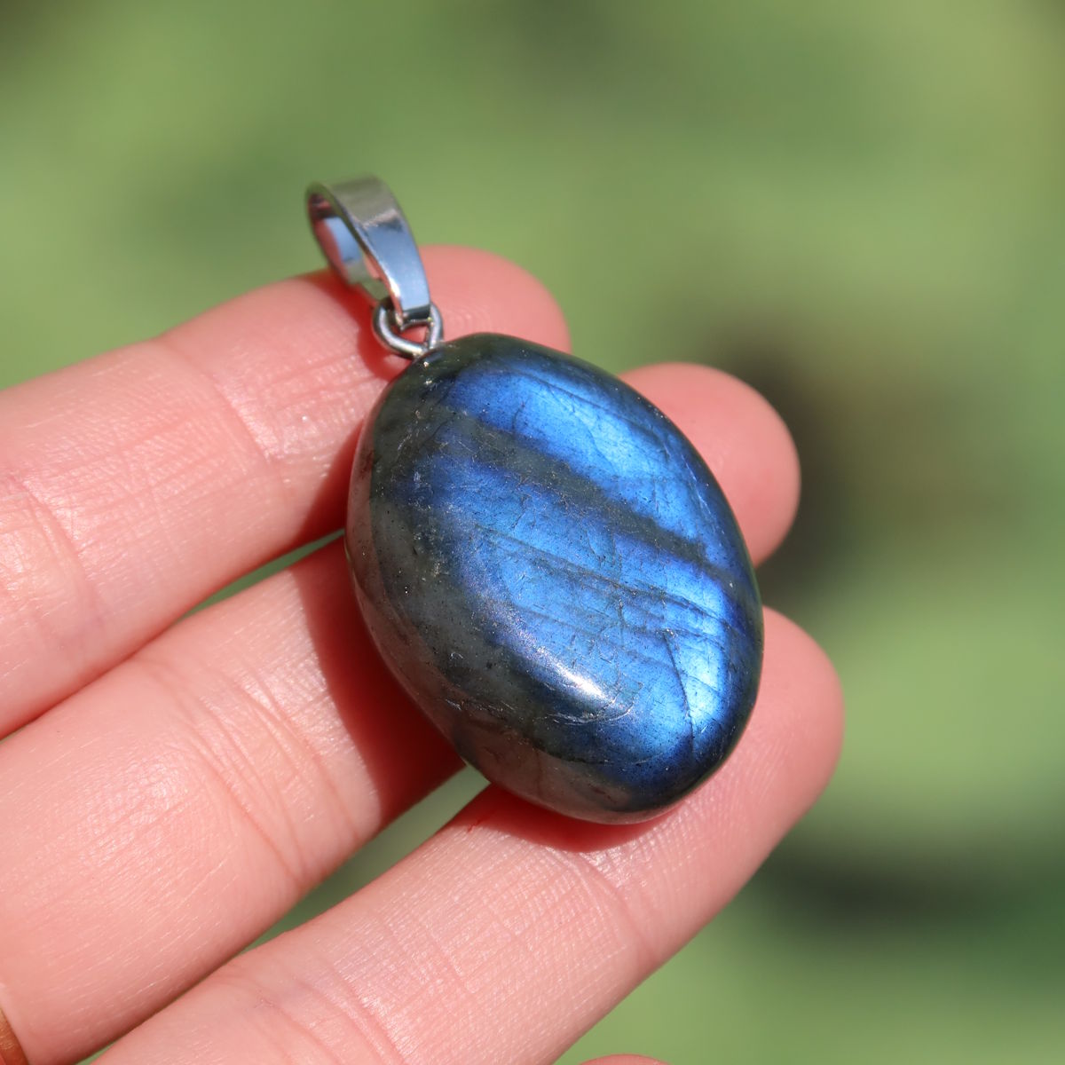 Natürlicher 1A Labradorit Anhänger, poliert mit Silberschlaufe 30mm - für Entspannung und Kreativität - UNIKAT Nr. 11 in Hand. Ansicht mit blauem Schimmer.