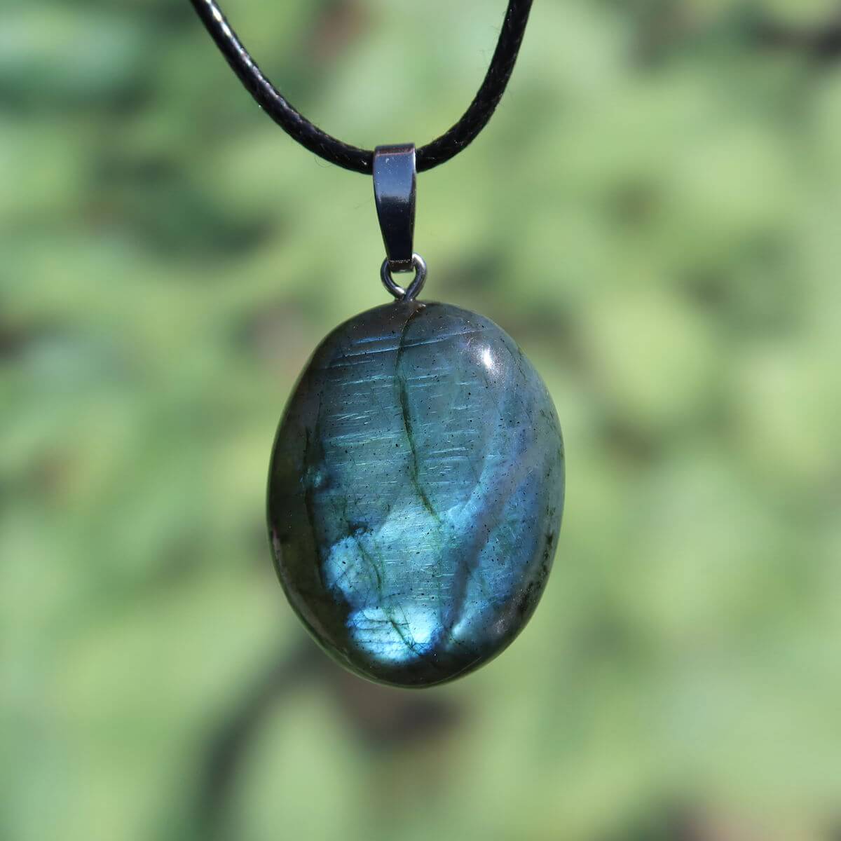 Polished Labradorite pendant with silver loop reflecting iridescent blues and greens, ideal for creativity and relaxation.