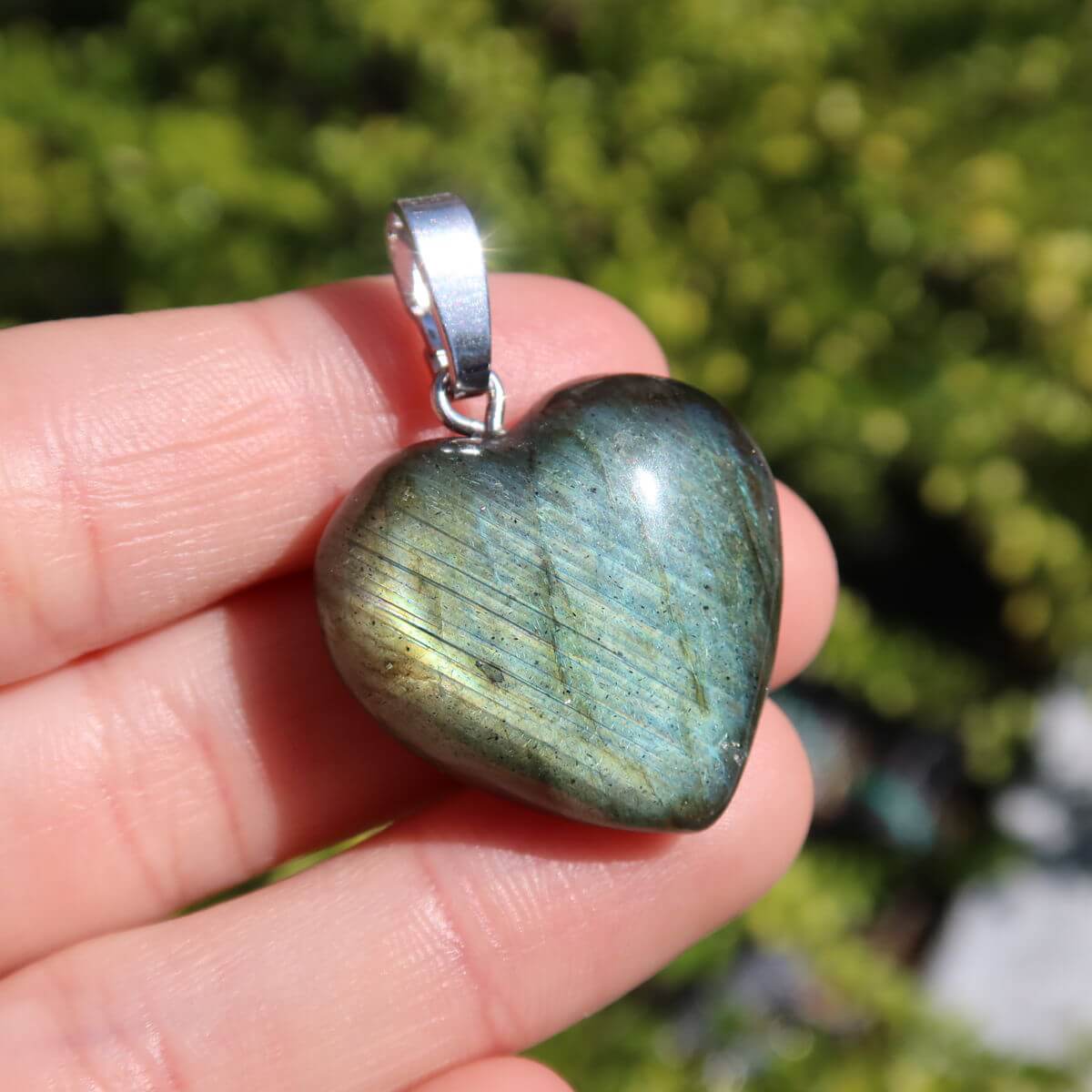 Labradorite heart pendant in vivid blue and green tones, showcasing its unique colors in sunlight, symbolizing intuition and spirituality.